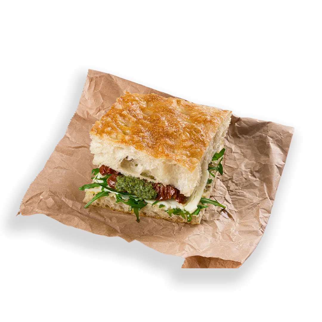 Sandwich with greens and cheese on brown paper against a white background