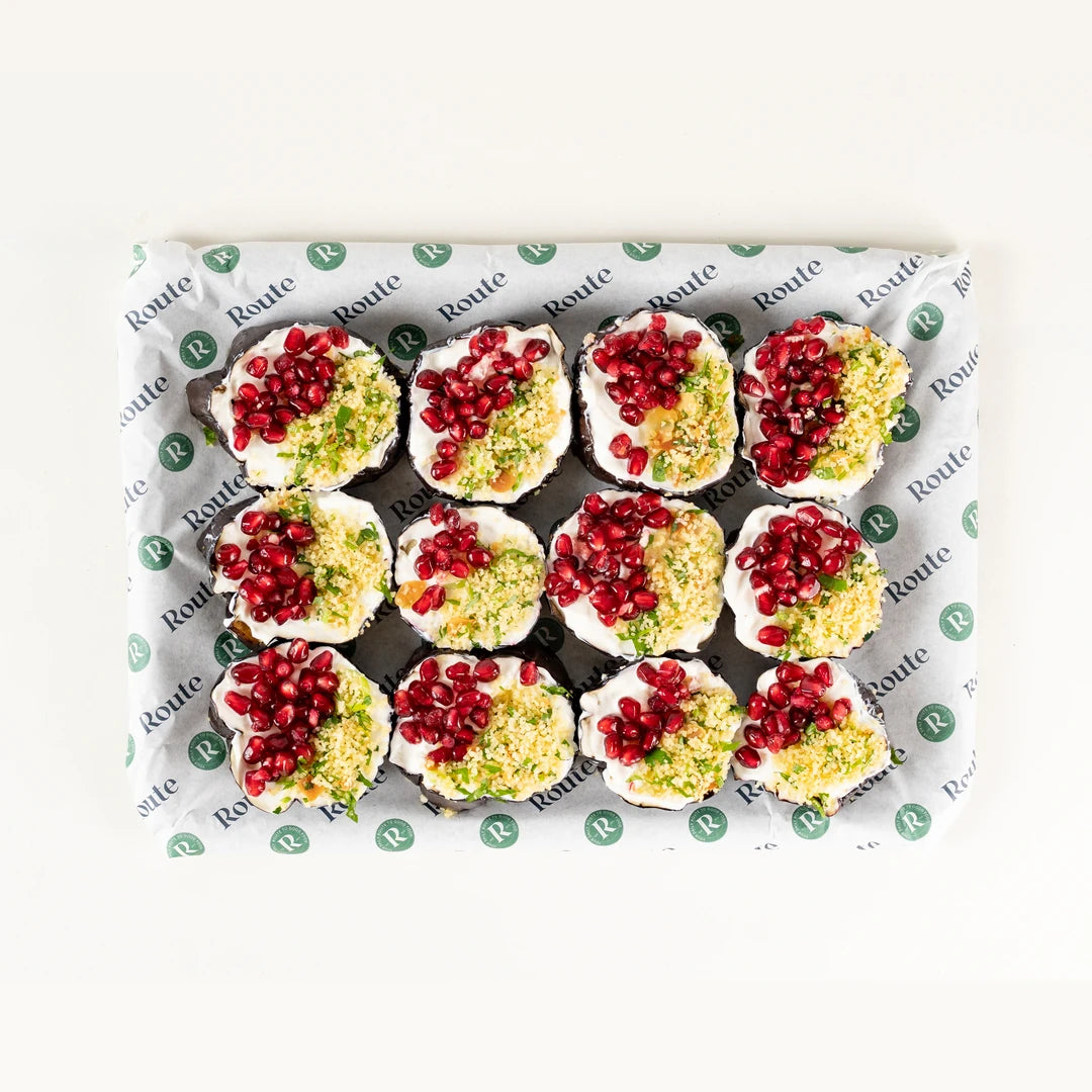 Aubergine Salad platter for six from above, aubergine discs topped with bulgur, pomegranate and yogurt on Route Catering paper