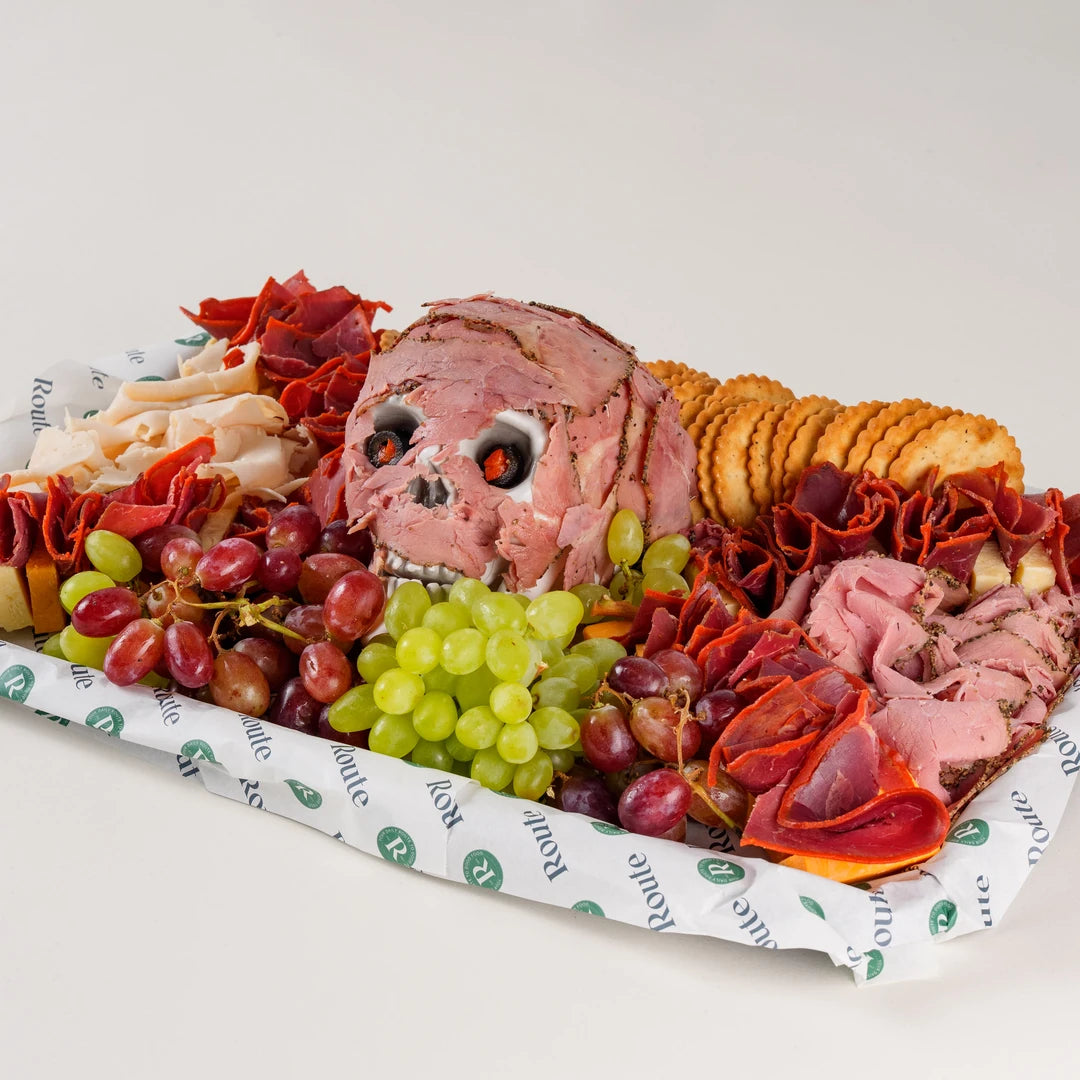 Halal Flesh Board Halloween charcuterie platter with pastrami skull, cheeses, grapes and breadsticks, serves 20 - Route Catering