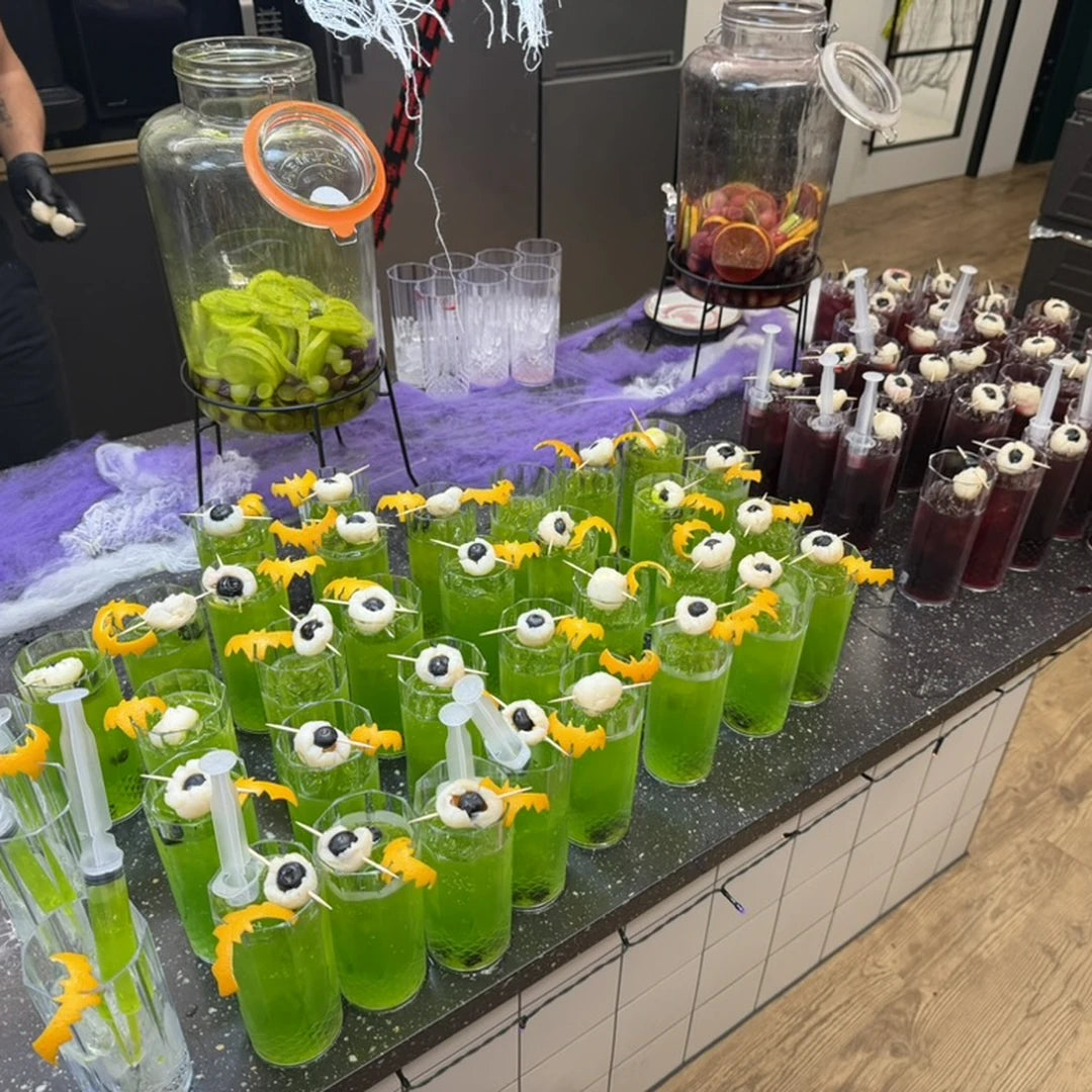 Halloween cocktails with jelly eyes and candy garnish lined up on the bar
