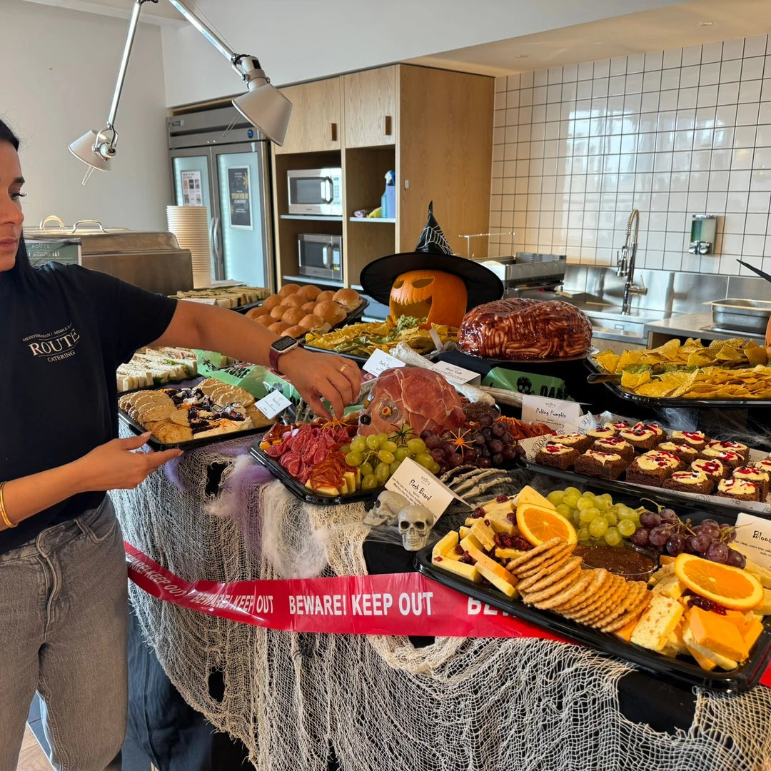 Route Catering team finishing a Halloween graze table with charcuterie, cheese and a carved pumpkin