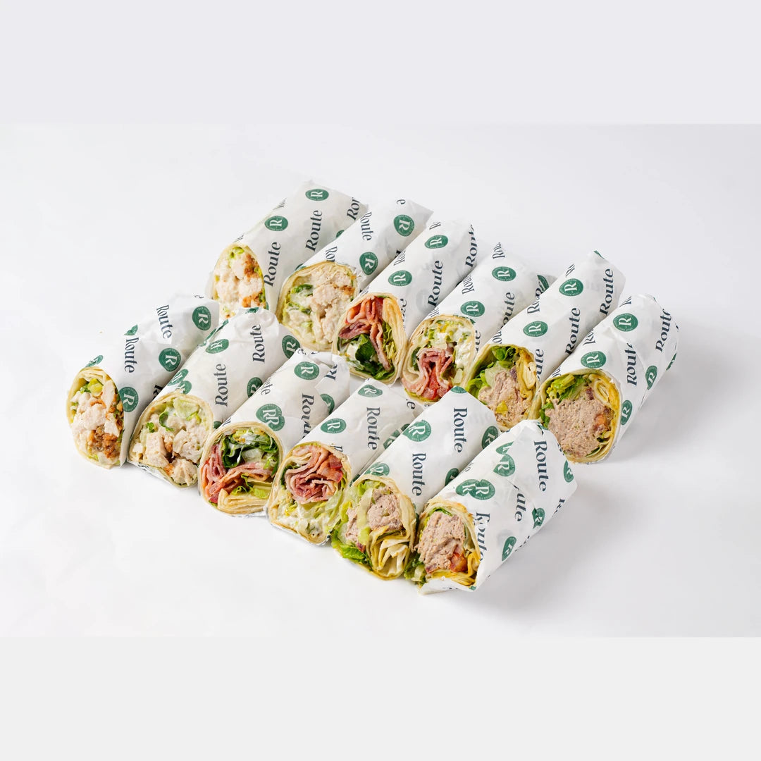 Meat sandwich wraps arranged on branded paper, office catering London, Route Catering