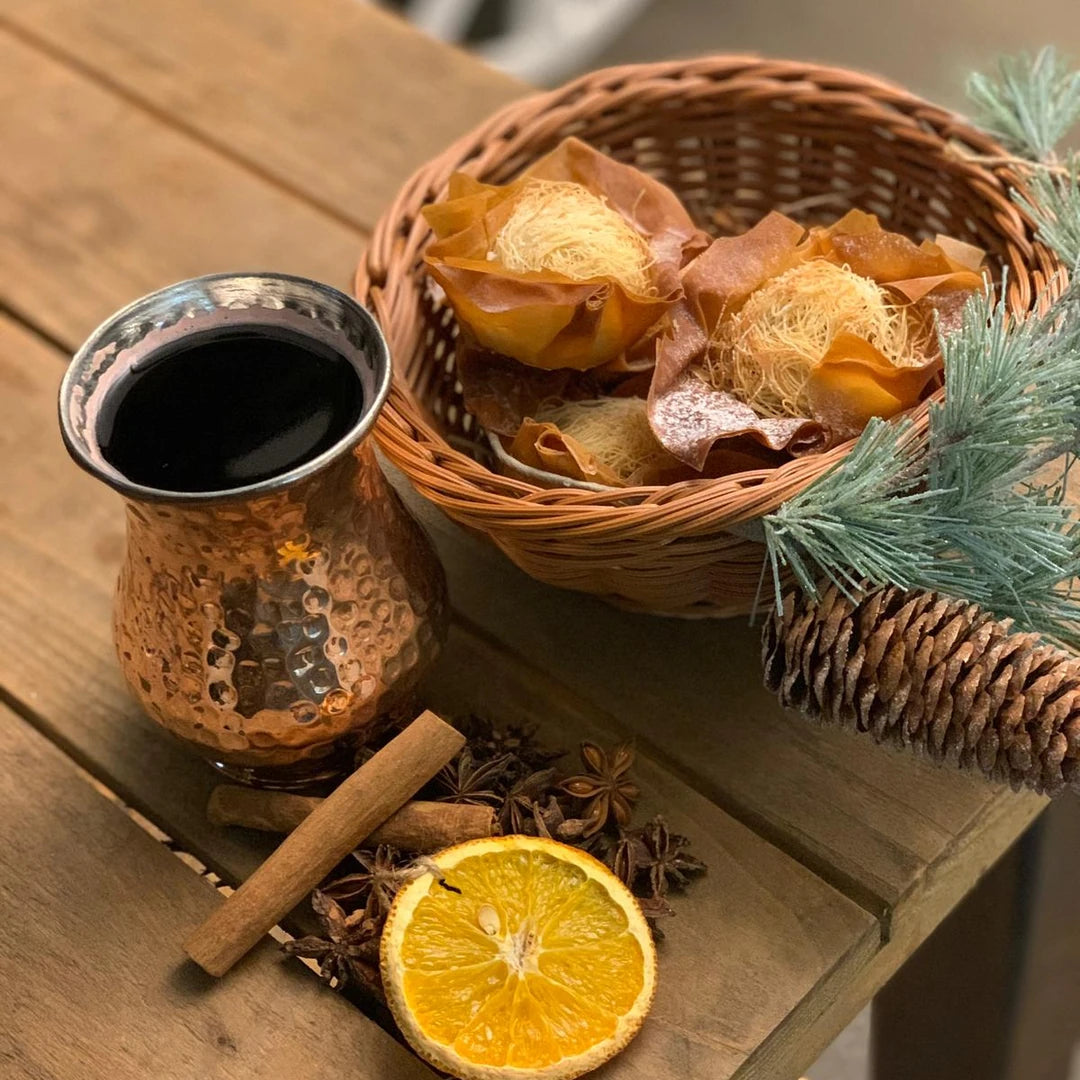 Mulled wine in a copper cup beside a basket of filo mince pies
