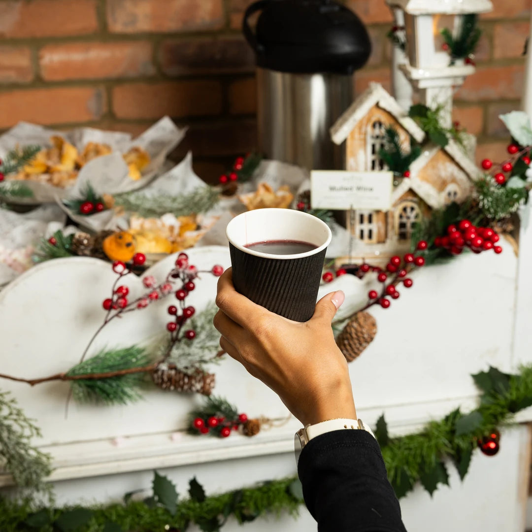 Guest holding a cup of mulled wine at the Route Catering Christmas cart with mince pies
