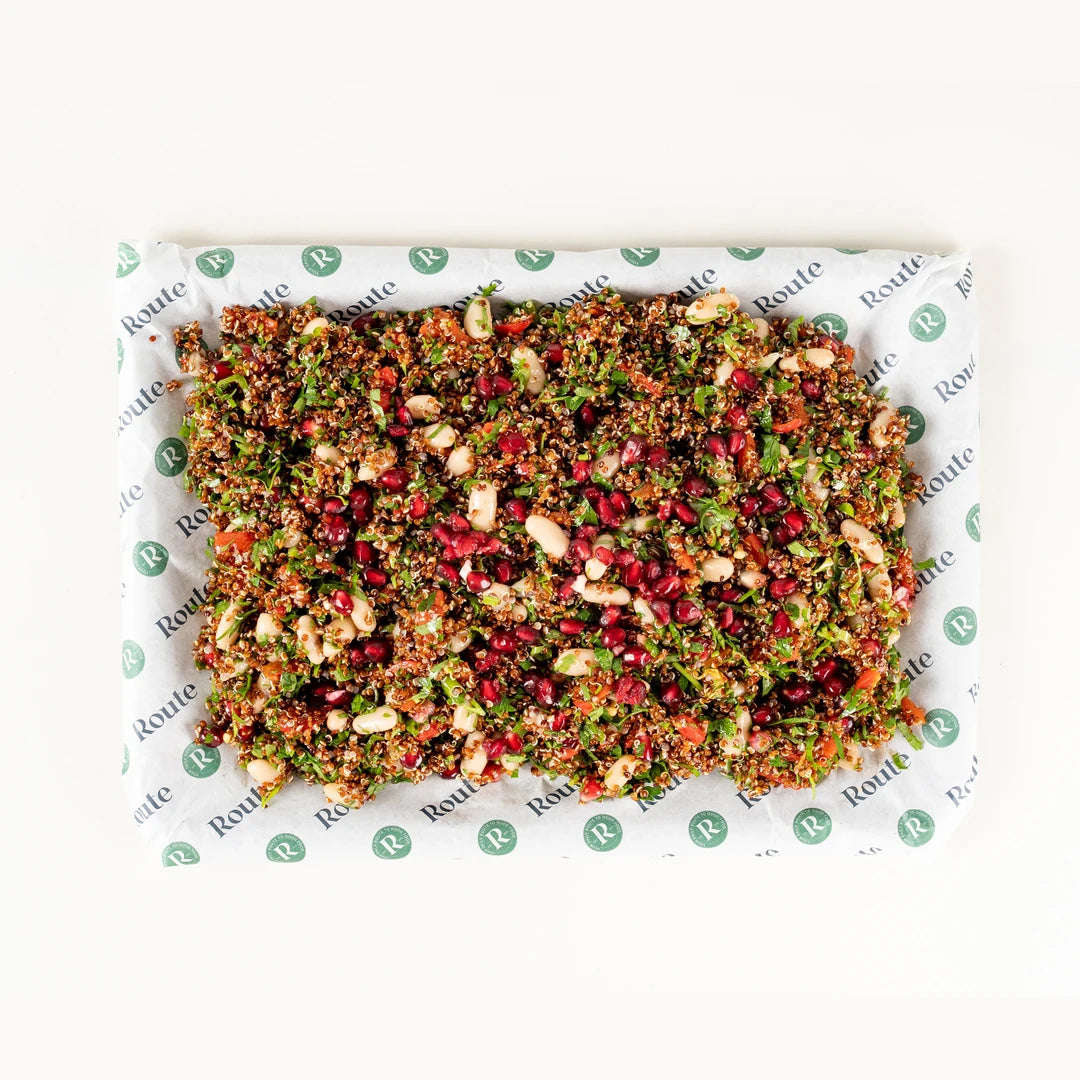 Red Quinoa Salad platter for six from above with cannellini beans, pomegranate and roasted red pepper on Route Catering paper